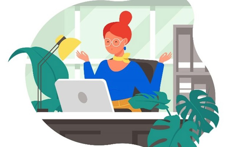Frau mit Laptop sitzt im Homeoffice zwischen Zimmerpflanzen und Schreibtischlampe.